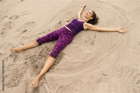 Latin Woman Wearing A Purple Leggings And Top While Lying On The Sand