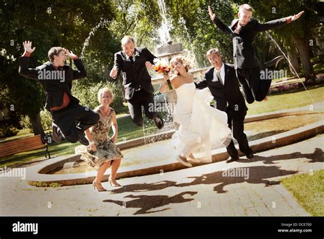 Wedding Party Jumping For Joy In Park Stock Photo Alamy
