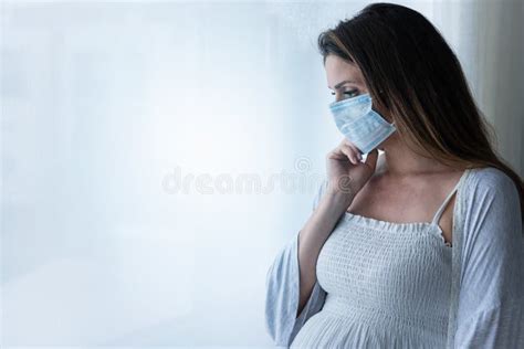 Pregnant Woman Standing By The Big Window With Face Medical Mask Stock
