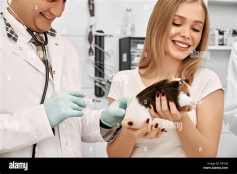 Charming woman holding cute hamster in hands. Vet doctor holding needle