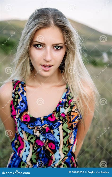 beautiful dreamy blonde girl with blue eyes in a light turquoise dress lying on the stones stock