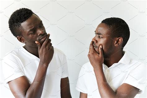 Portrait Of Two Cautious And Thoughtful Black Guys Wearing White T Shirts Looking At Each Other