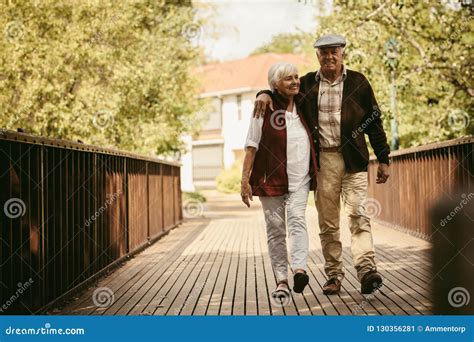 Happy Elderly Couple Walking Through A Park Stock Image Image Of