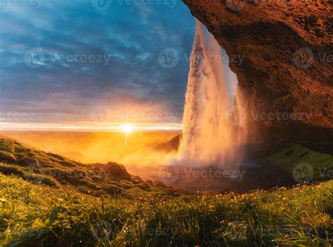 Beautiful Seljalandsfoss Waterfall Flowing And Midnight Sunset Shining