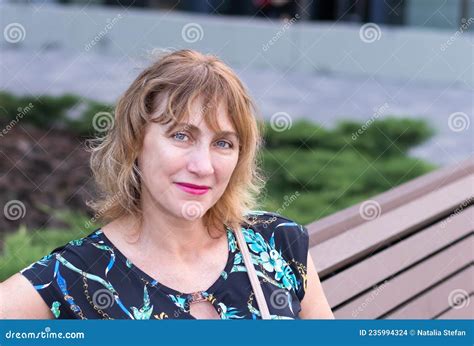 woman a european middle aged 50 55 years old a pretty blonde sitting on a park bench stock