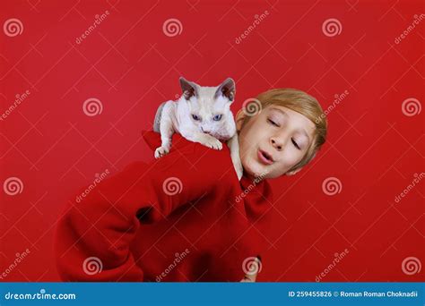 wesoły chłopiec w czerwonym kostiumie z małym białym kociakiem z niebieskimi oczyma siedzącymi