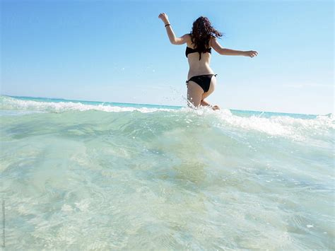 Woman In A Black Bikini Running Through The Sea Water By Stocksy Contributor Lucas Ottone
