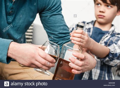 Deswegen sollte so ein alkoholiker entzug nur unter ärztlicher aufsicht passieren. Junge und Vater Alkoholiker zu Hause Sohn holding Flasche ...