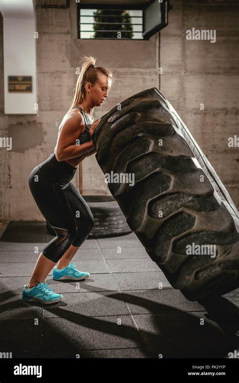 Young Muscular Woman Flipping A Tire On Cross Fit Training At The Gym