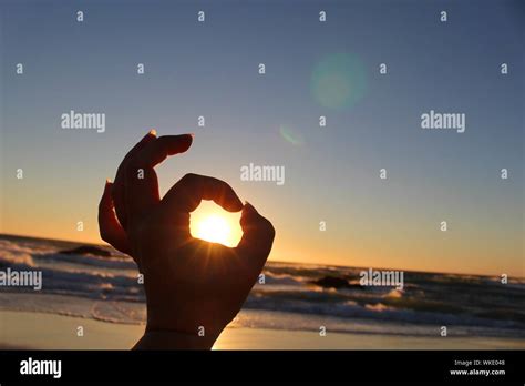 Optical Illusion Of Hand Holding Sun At Beach Stock Photo Alamy
