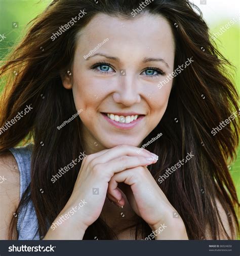 Portrait Of Beautiful Dark Haired Smiling Girl Propping Up Her Face At Summer Green Park Stock