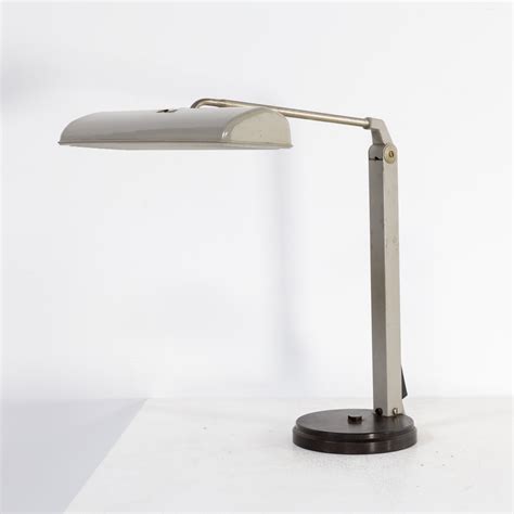 It has a round black metal foot, silver grey metal boomerang shaped arm and black circular shade. 60s Waldmann Leuchten table lamp - BarbMama