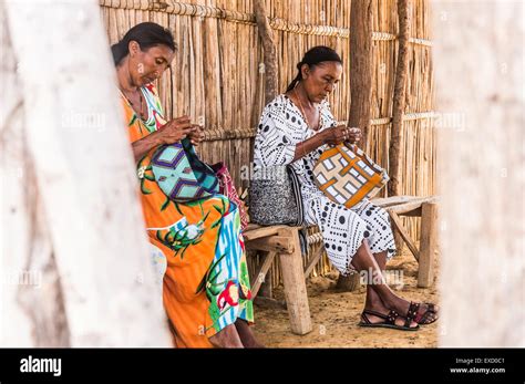 Dos mujeres indígenas Wayuu tejiendo mochilas o bolsos tradicionales en una ranchería o