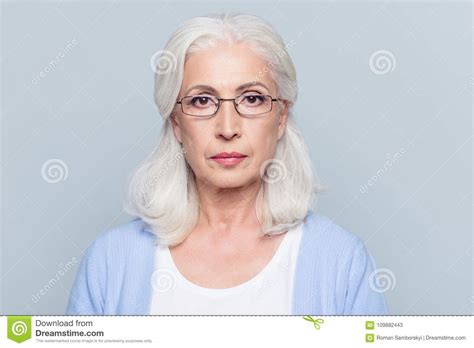 Close Up Portrait Of Serious Aged Charming Woman In Glasses Over Grey