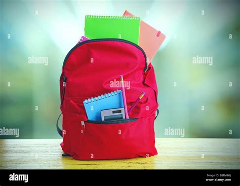 Red Bag With School Equipment On Wooden Table In Classroom Stock Photo