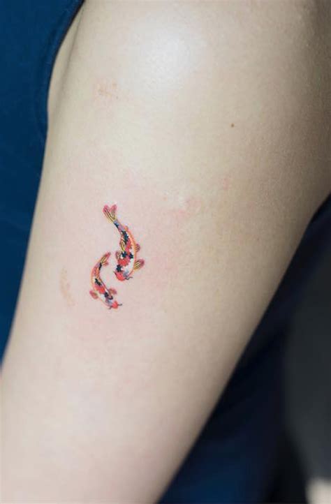 A Womans Arm With A Small Tattoo Of A Koi Fish On It