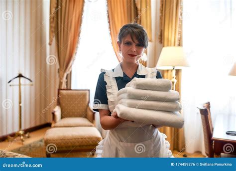Only The Freshest Hotel Maid In Uniform Smiling While Holding Stack Of