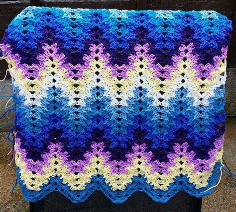 A Crocheted Blanket That Has Been Made With Blue Yellow And White Yarn