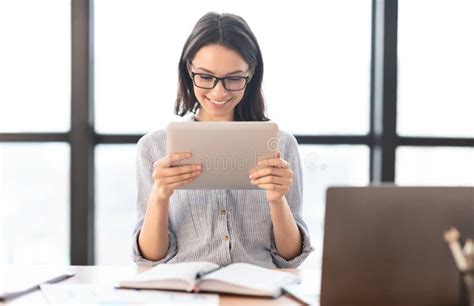 Young Girl Holding Tablet And Using Laptop At Modern Office Stock Image