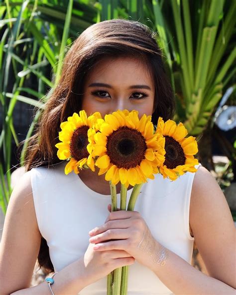 A Woman Holding A Bunch Of Sunflowers In Her Hands