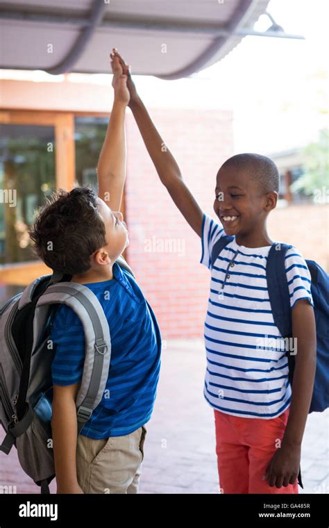 Playful Classmates Giving High Five At Corridor Stock Photo Alamy