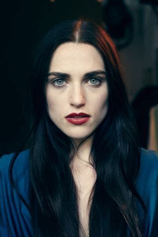 A Woman With Long Black Hair And Blue Eyes Is Posing For The Camera