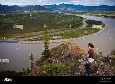 A Woman Sits On A Rock Enjoying A View Of The Yukon River Eagle