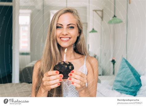 Young Beautiful Blonde Woman In The Bed Blowing A Candle In A Chocolate