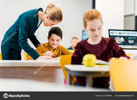 Young Teacher Helping Schoolchildren Studying Desks — Stock Photo