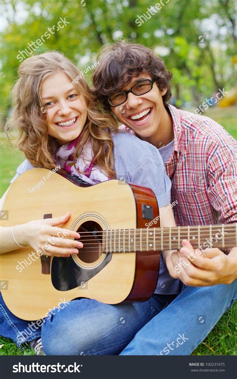 Joyful Guy Teaching Beautiful Teenage Girl Play Guitar In