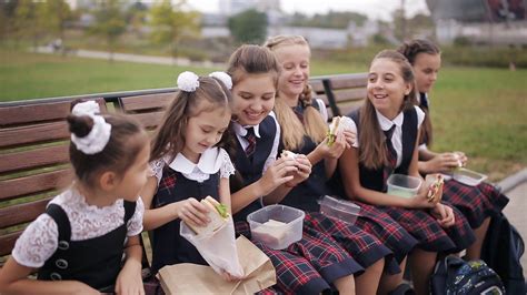 Girls College student wearing the same school uniform eating sandwiches ...