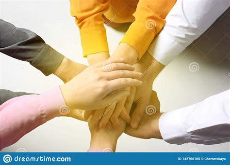 Group Of Volunteers Putting Their Hands Together On Light Background