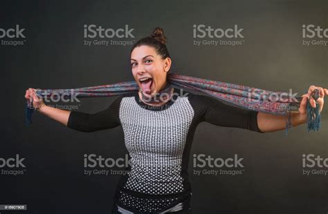 Attractive Woman Choking Her Self With A Silk Scarf And Sticking Her Tongue Out While Smiling