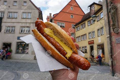 Giant German Sausage With Mustard In A Bun Held Up High Editorial