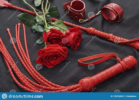 playing bdsm games top view of bdsm leather kit handcuffs whip and roses against of black silk