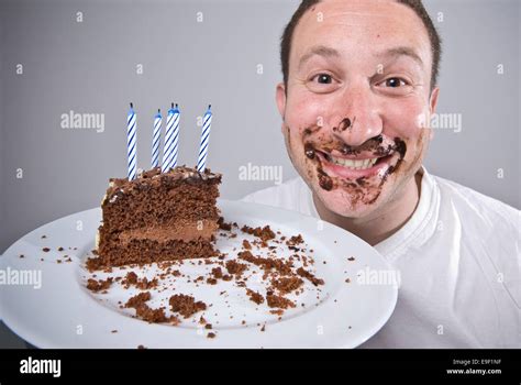A Man Holds Up A Slice Of Chocolate Birthday Cake Looking Like Hes