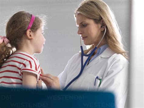 Female Doctor Listening To A Young Girl Heart Using A Stethoscope In A