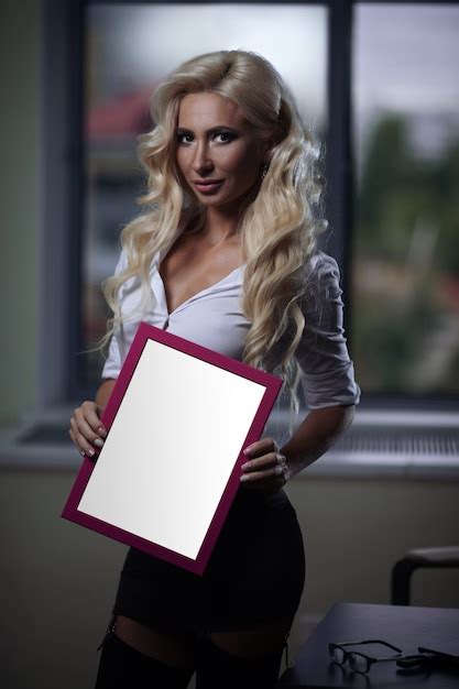 empleada sexy en la oficina posando con un cartel en sus manos foto premium