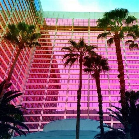 Palm Trees In Front Of A Building With Pink And Blue Windows On The