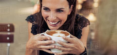 Close Up Shot Of Cheerful Young Woman Drinking Coffee At A Cafe And