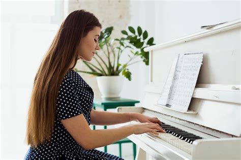 Side View Of A Beautiful Young Woman Playing The Piano Free Photo