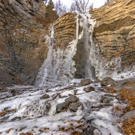 Frozen Waterfall On A Rugged And Eroded Cliff With Trees And Sky