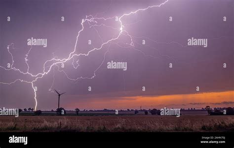 Severe Lightning At Sunrise Pictured Around A Wind Turbine Stock Photo