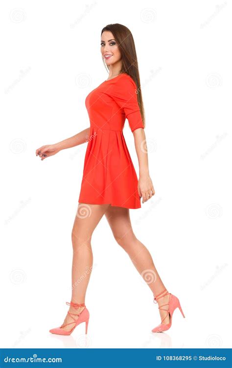 Beautiful Young Woman In Red Mini Dress And High Heels Is Walking Stock