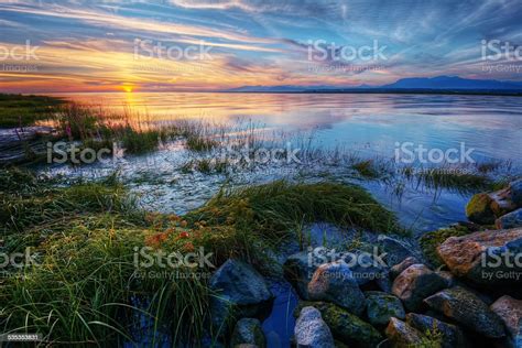 Relaxing Summer River Sunset With Green Grass And Distant Mountains