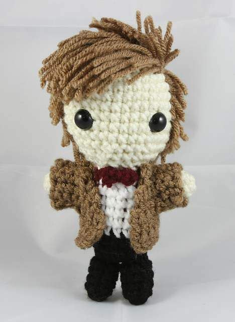 A Small Crocheted Doll Wearing A Brown Jacket And Bow Tie With Black Pants