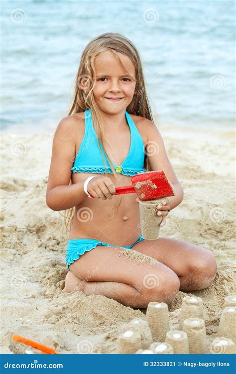 Маленькая девочка играя с песком на пляже Стоковое Изображение изображение насчитывающей