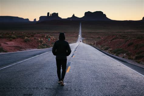 Anonymous Person Walking Alone Down A Desert Country Roadsunset At