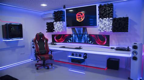A Gaming Room With Two Monitors Speakers And A Red Chair In Front Of It