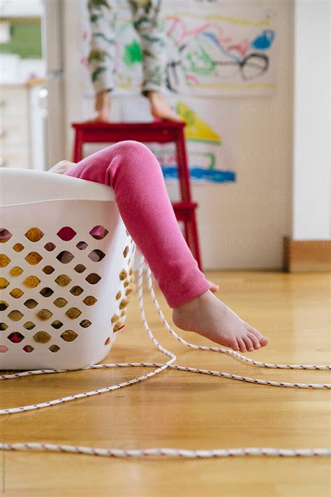 Child At Home Playing In The Laundry Basket With Feet By Stocksy